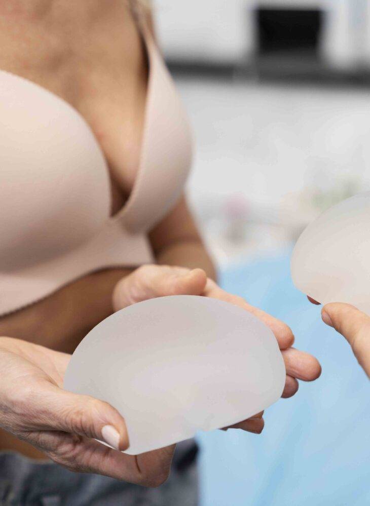 close up hands holding breast implants copy scaled