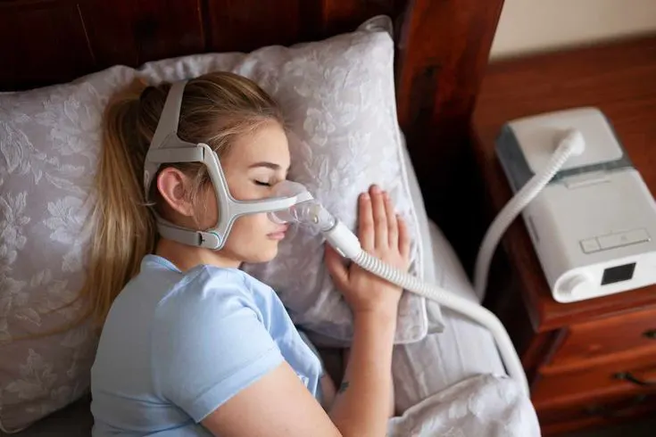 صورة لجهاز CPAP مع قناع يرتديه شخص نائم